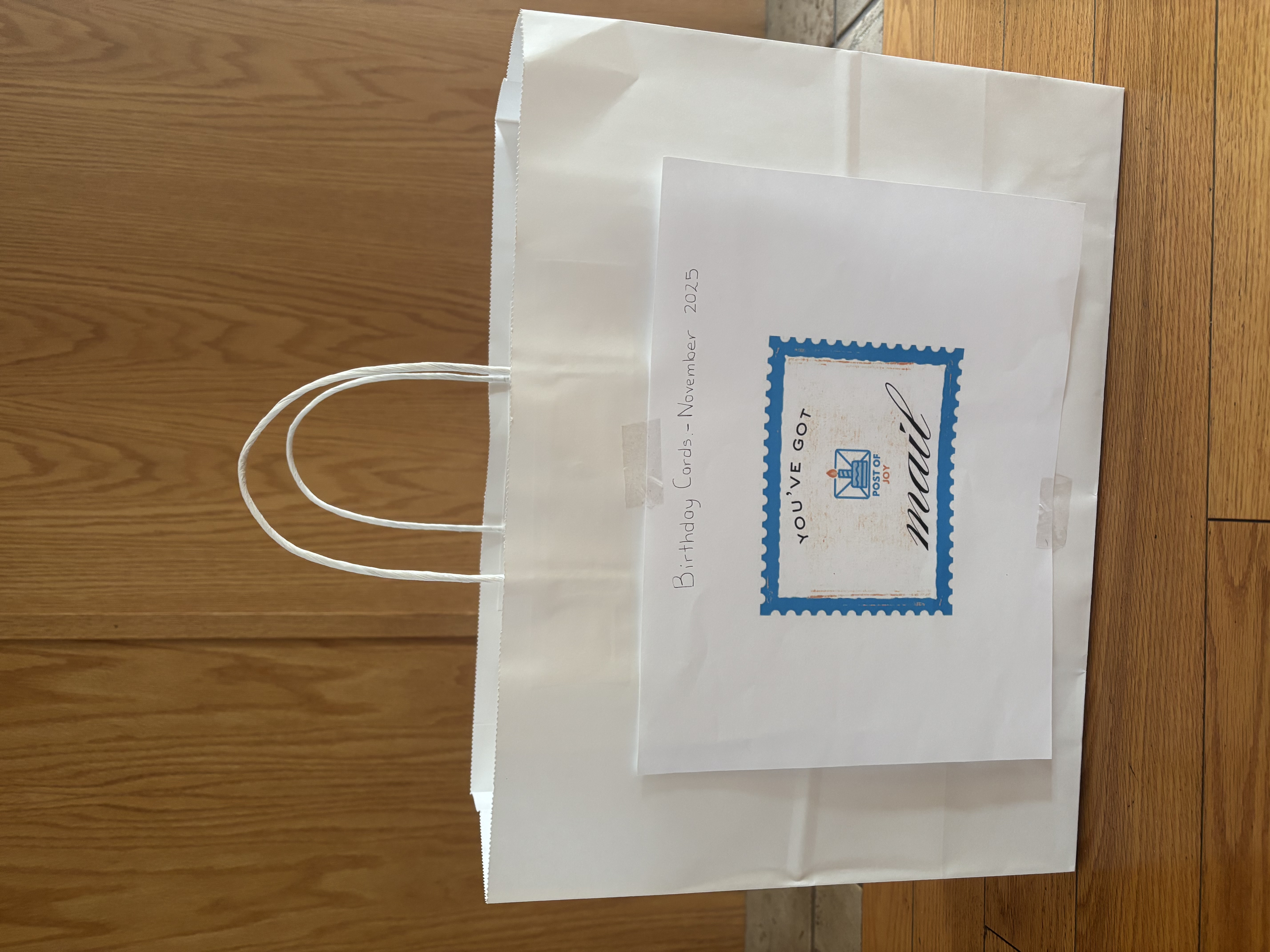 A white Post of Joy birthday card delivery bag with a mail label.